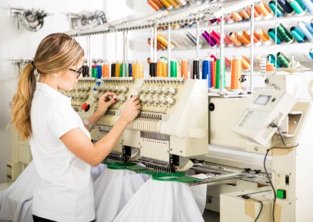 Women setting up an industrial embroidery machine for apparel decoration